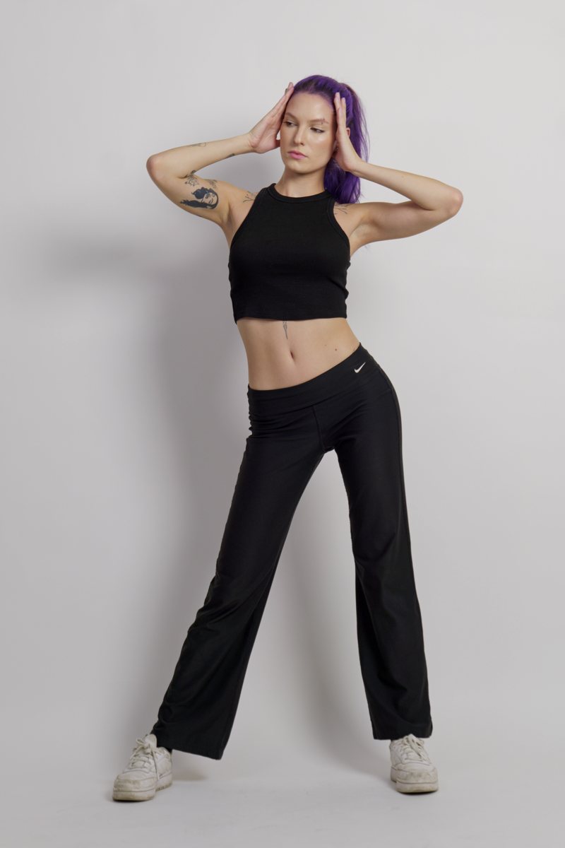Iulia standing against a grey studio backdrop, hands raised to her head